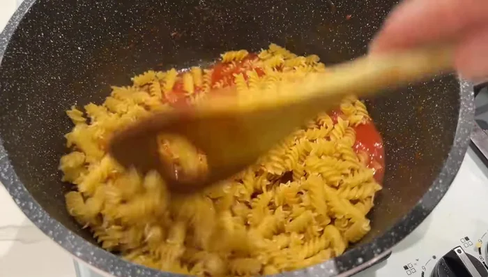 Préparation des pâtes à la sauce tomate : Râper 4 tomates. Ajouter du concentré de tomates, du sel, du poivre, de l'ail, de l'huile d'olive et du persil. Faire cuire les pâtes et ajouter la sauce et du fromage.