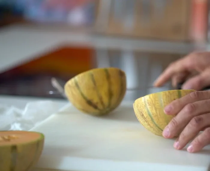 Préparation de l'apéritif : Laver et couper les melons en deux. Retirer les graines et utiliser une cuillère parisienne pour faire des boules de melon. Mélanger la chair restante avec du jus de citron et réfrigérer.