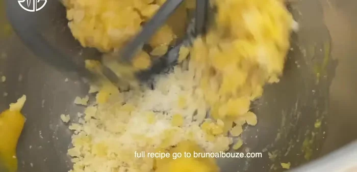 Mélanger une tasse du mélange d'amandes avec le beurre fondu et réserver. Tamiser la farine avec la levure chimique et ajouter la partie réservée contenant le beurre. Étaler le mélange dans un plat de cuisson et cuire environ 25 minutes.