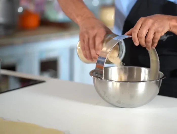 Préparer le cercle à pâtisserie : beurrer et saupoudrer de sucre brut. [50.52]