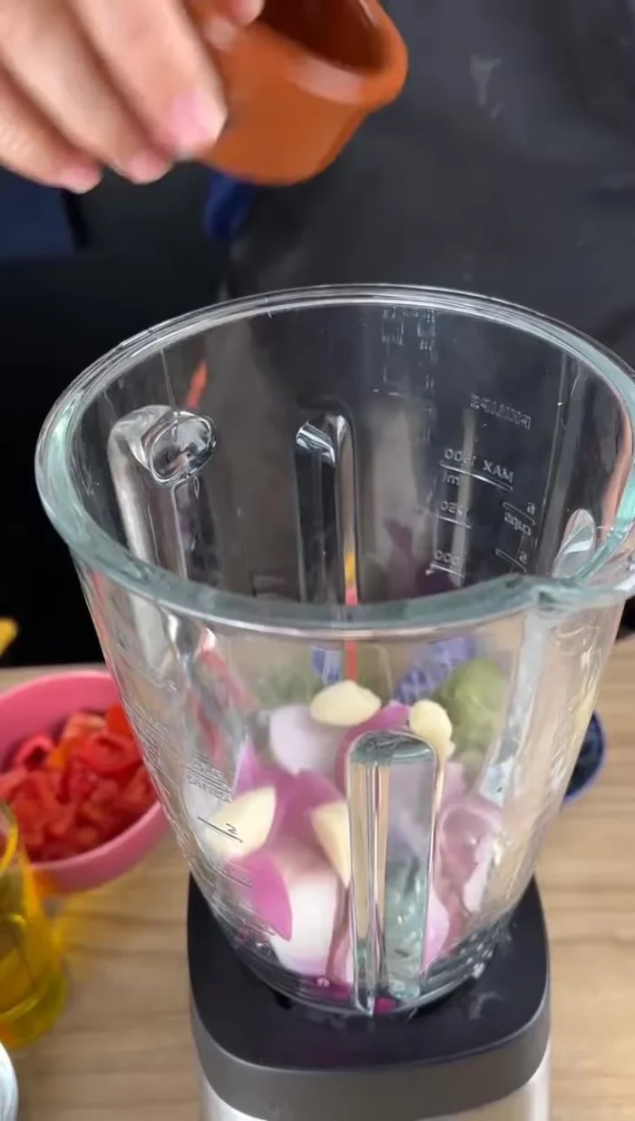Dans un mixeur, mélanger les oignons rouges, l'ail, le poivron, la coriandre ou le persil, les tomates, l'huile d'olive, le sel, l'eau et le lait de coco.
