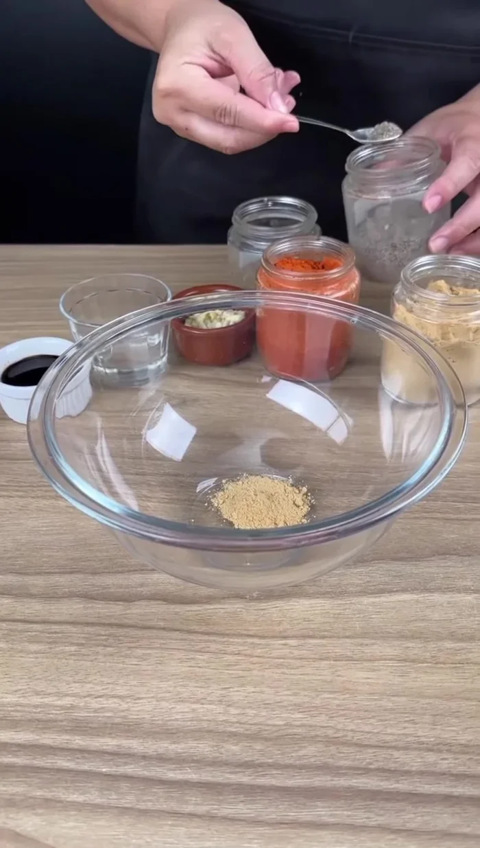 Préparez l'assaisonnement : mélangez dans un bol l'ail en poudre, le poivre noir, le paprika, l'origan, les gousses d'ail hachées, le vinaigre et la sauce soja. (45.079)