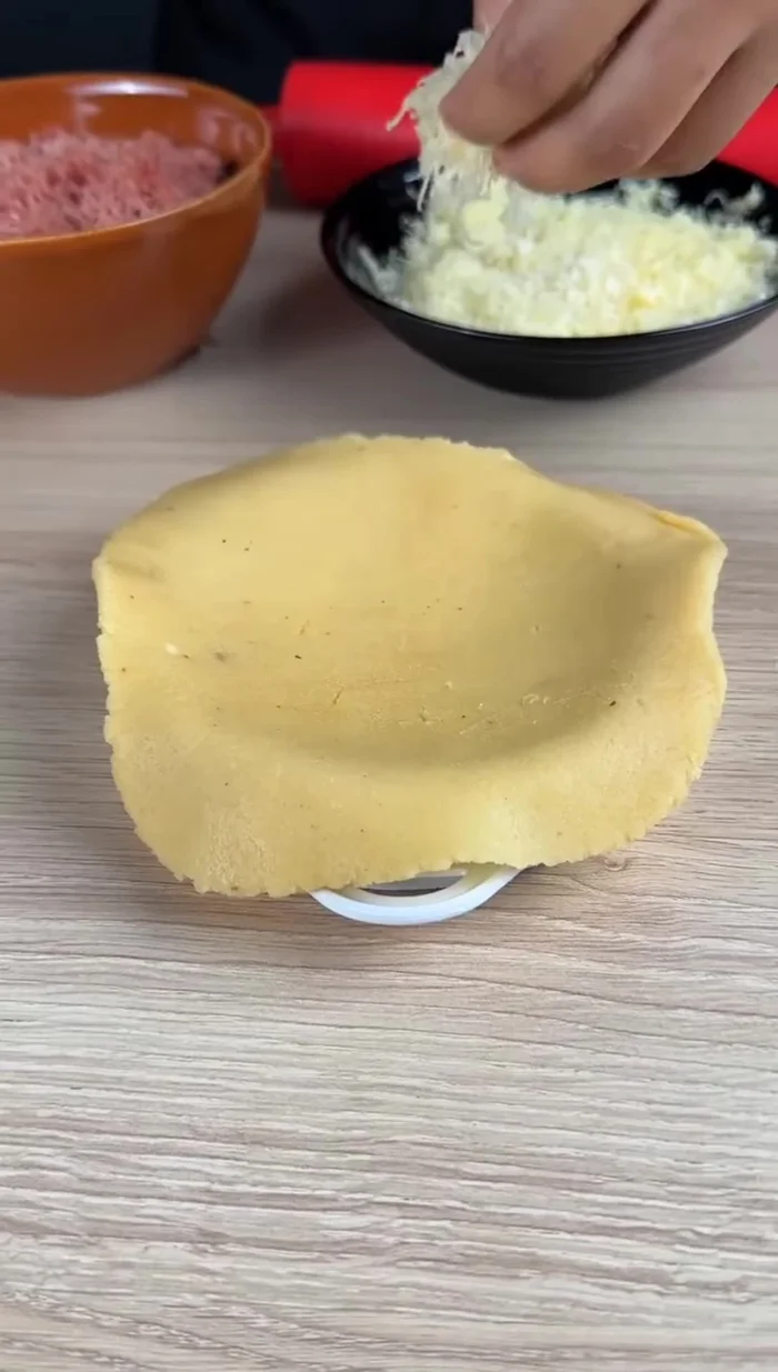 Ajouter du fromage au centre, puis du jambon râpé, et recouvrir d'un peu plus de fromage.