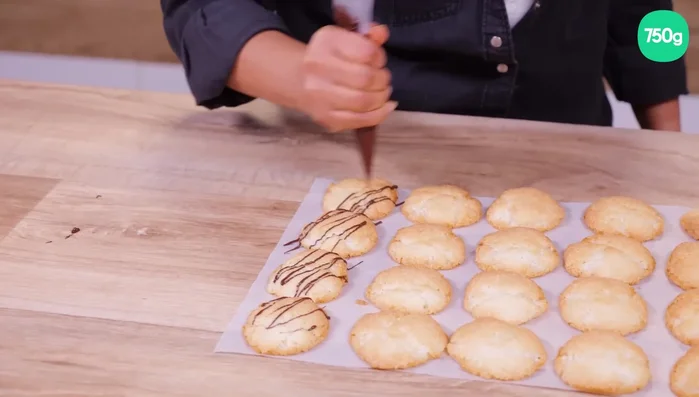 Faire fondre du chocolat noir et décorer les macarons.