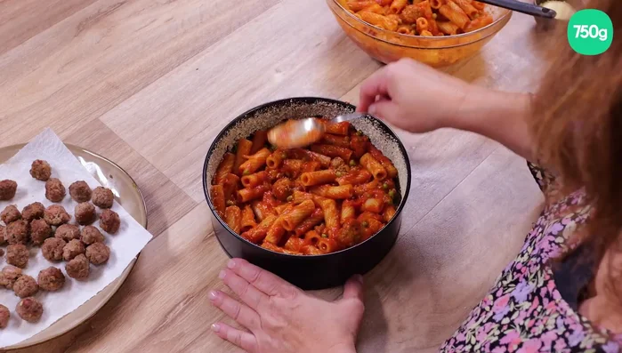 Étaler la moitié des pâtes dans le moule, tasser. Ajouter une couche de mozzarella égouttée et tassée. Ajouter les boulettes restantes sans sauce.