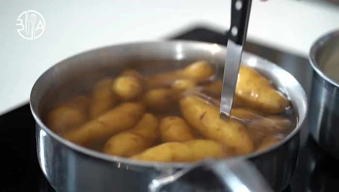 Égouttez et épluchez immédiatement les pommes de terre. Pour les garder chaudes, placez-les dans un grand bol recouvert de film plastique avec un trou au centre.