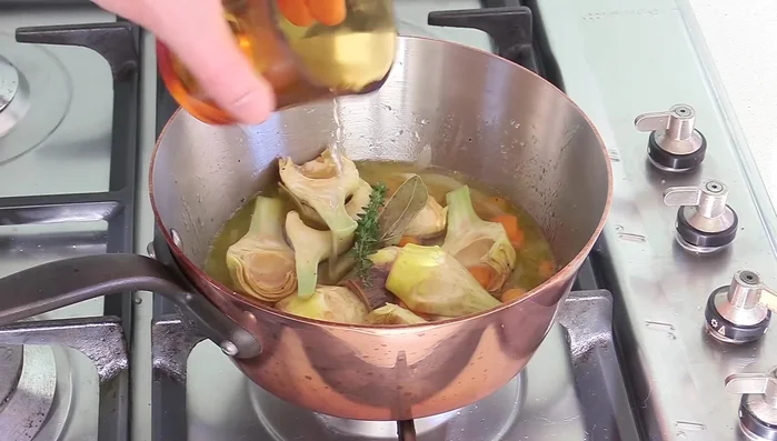 Ajouter le vin blanc et compléter avec de l'eau pour à peine couvrir les artichauts.