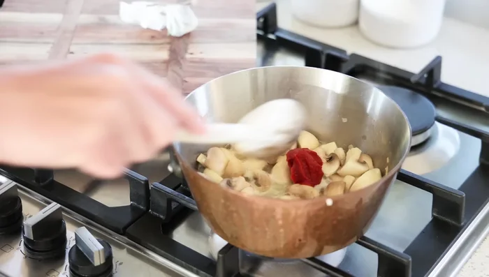 Ajouter la pâte de tomate et le sachet d'aromates, enfoui sous les champignons.