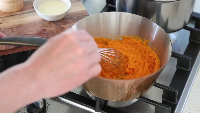 Incorporer de la crème à la purée de carottes, réchauffer doucement et assaisonner. (808.079)