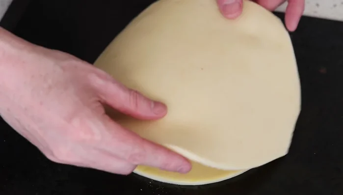Fermeture du pithivier : Recouvrir avec le deuxième disque de pâte. Sceller les bords en pressant avec les doigts (652.64). Découper l’excédent de pâte (699.68).