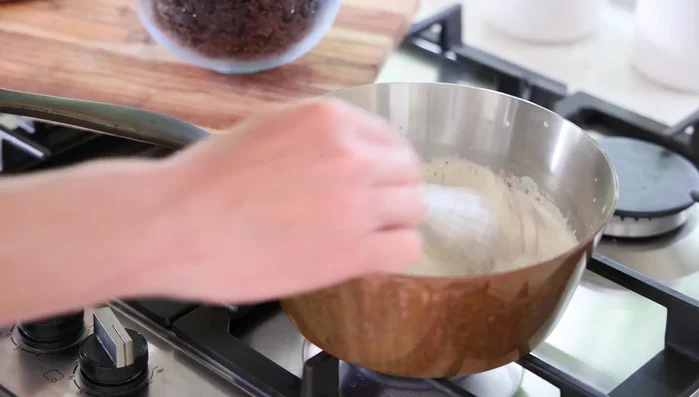 Incorporer petit à petit le chocolat dans la crème chaude, en remuant constamment jusqu'à obtenir une consistance lisse et homogène, comme une mayonnaise. Si la ganache commence à se fendre, éteindre le feu et ajouter de l'eau froide.