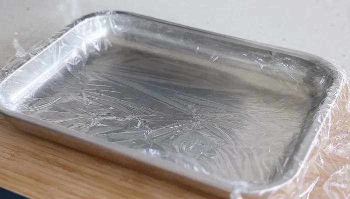 Verser la ganache dans un récipient plat tapissé de film alimentaire. Couvrir d'un autre film alimentaire.