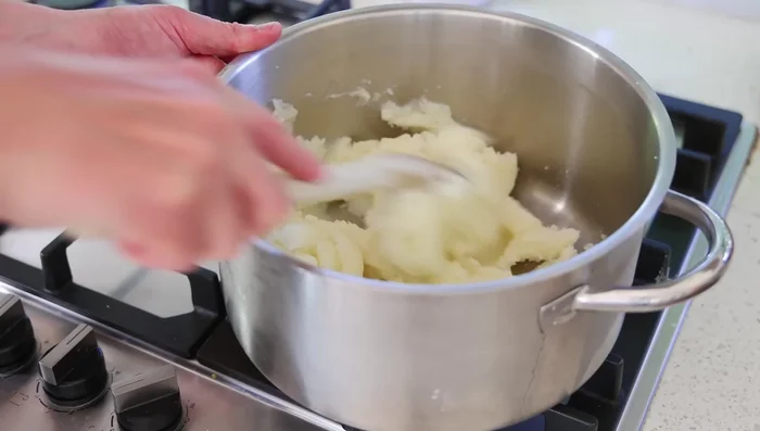 Dans une casserole à feu moyen, écraser les pommes de terre et les faire cuire 4-5 minutes en mélangeant, pour évaporer l'humidité.