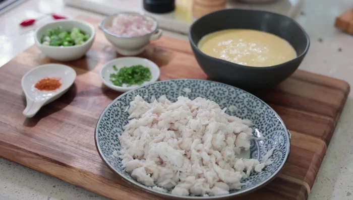 Mélangez le poisson émietté avec la moitié du poids du poisson en pâte à beignets, ainsi que les aromates (oignon de printemps, ciboulette, ail, piment, poivre, sel).