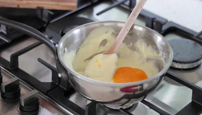 Ajouter le jaune d'œuf, hors du feu, en mélangeant avec une cuillère.