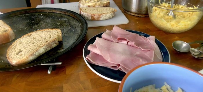 Montage : Étaler une couche de béchamel sur une tranche de pain (272.12). Ajouter une couche de fromage mélangé, puis de jambon (282.04). Étaler de la moutarde sur le jambon, ajouter encore du fromage, et recouvrir avec la seconde tranche de pain (298.639).
