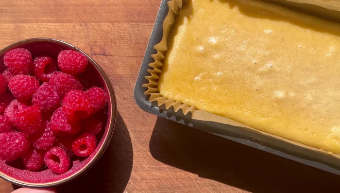 Sortir le gâteau du four, ajouter 125g de framboises fraîches sur le dessus et répartir uniformément.