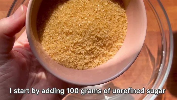 Verser 100g de sucre non raffiné dans un grand bol.