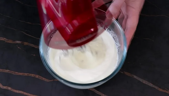 Monter la ganache nuage fleur d'oranger. Pocher sur la tarte, creuser des trous avec une cuillère chaude et garnir de praliné. Décorer de poudre de pistache et de pistaches.