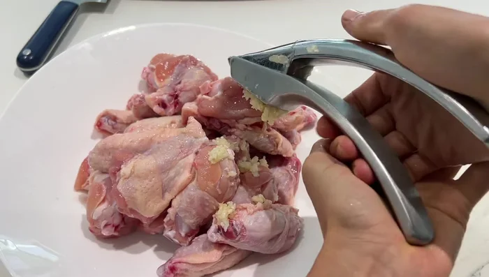 Préparation des ailes de poulet : couper les ailes de poulet en deux, les assaisonner avec de l'ail, du paprika, du gingembre, du curcuma, du sel, du poivre, de la coriandre et de l'huile d'olive. Ajouter une cuillère à soupe de miel pour plus de croustillance.