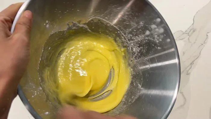 Préparation de la crème pâtissière : mélanger de la maïzena (ou de la crème vanillée), du sucre et des œufs. Ajouter du lait bouilli avec du sucre.
