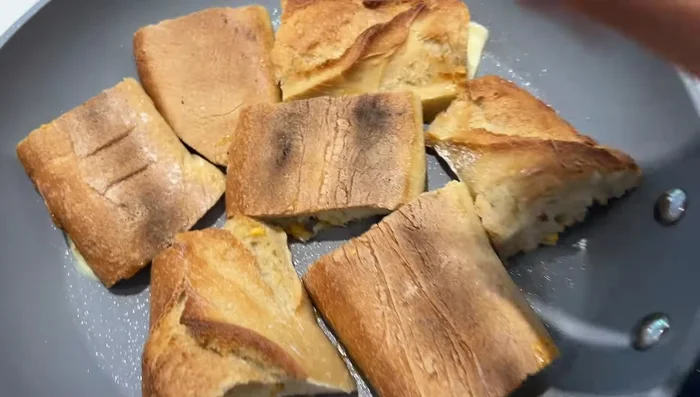 Préparation des petits pains au fromage : disposer des morceaux de pain avec du fromage et faire fondre au four ou dans une poêle.