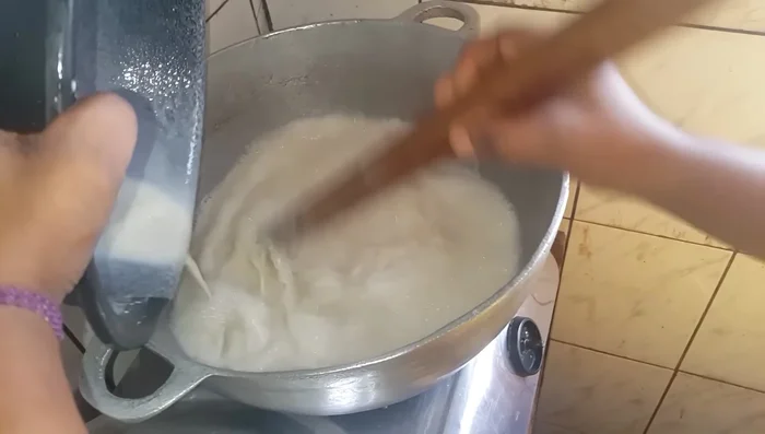 Préparer le couscous maïs : faire bouillir de l'eau, ajouter la farine de couscous et mélanger pour éviter les grumeaux. (907.6)