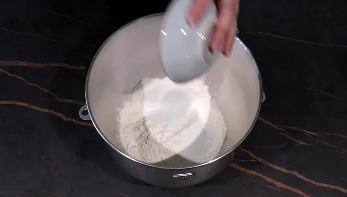 Dans le bol du robot, mélanger la farine, le sucre et le sel. Creuser un puits, y ajouter l’œuf et le mélange levure-lait. Pétrir 8 minutes. (100.92)