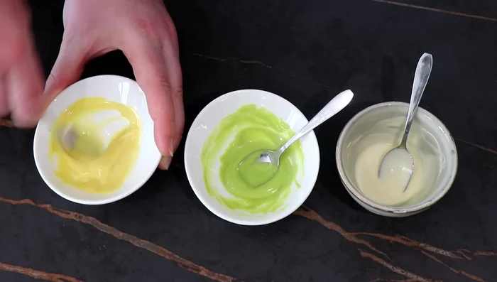 Partager le chocolat blanc en trois, colorer une partie en vert, une autre en jaune (facultatif).