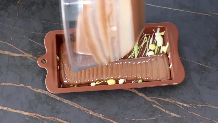 Verser le chocolat tempéré dans le moule, répartir sur toute la surface, y compris les bords. Travailler vite !