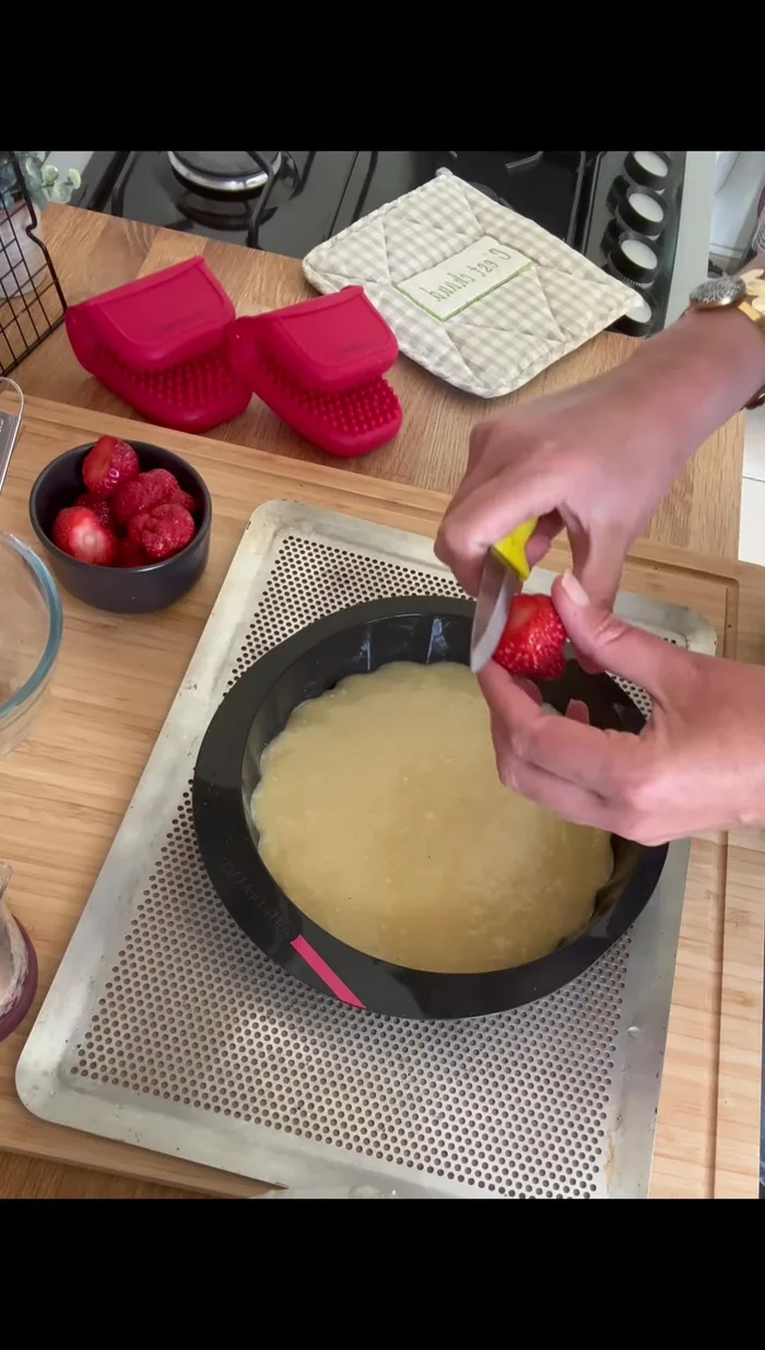 Couper les fraises en morceaux (pas trop petits) et les enfoncer légèrement dans la pâte.