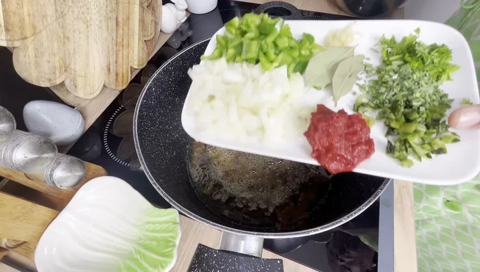 Préparation de la sauce tomate: faire revenir les oignons, poivrons verts, ciboulette et persil. (Préparation du ragout)