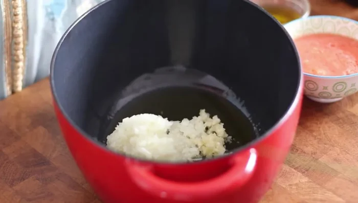 Préparation des Tripes : Dans une cocotte, faire revenir un oignon râpé avec de l'ail, de la coriandre fraîche, et les tripes de mouton préalablement lavées et coupées en morceaux (bien laver à l'eau vinaigrée).