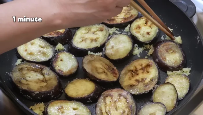 Après 12 minutes, ajouter la moitié du gingembre râpé et cuire 1 minute. Puis ajouter la moitié de la sauce réservée pour les aubergines (celle avec plus d'eau). Couvrir et cuire 1 minute de chaque côté.