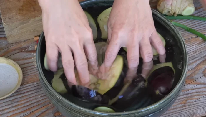 Rincer les aubergines pour enlever le sel et les presser légèrement pour retirer l'eau.