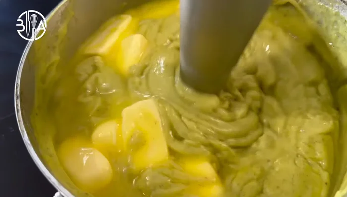 Ajouter la pâte de pistache et le beurre froid, mixer au mixeur plongeant.