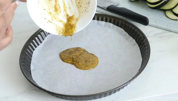 Étaler la marinade dans un moule à tarte tapissé de papier cuisson.
