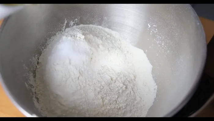 Dans le bol du batteur, ajouter la farine, l'huile végétale, le blanc d'œuf, le vinaigre, l'œuf et le mélange lait-levure. Pétrir pendant 10 minutes (ajouter plus de farine si la pâte est trop collante).