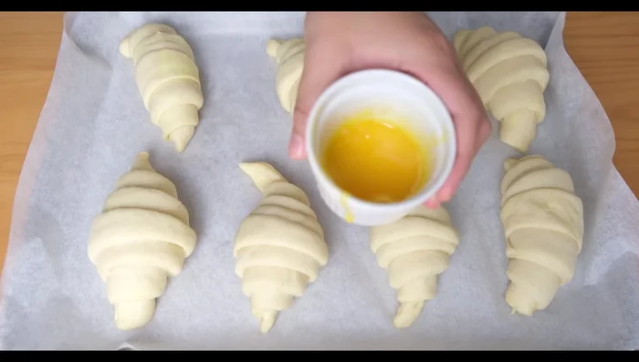 Badigeonner les croissants avec un mélange de jaune d'œuf et de lait frais.