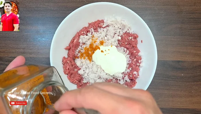 Dans un bol, mélanger la viande hachée avec les oignons pressés, le caillé égoutté, la noix de muscade, le jatri, le sel, le curcuma, le poivre noir, le cumin, la coriandre, les piments verts, la farine de pois chiches, l’œuf et la pâte de gingembre-ail.