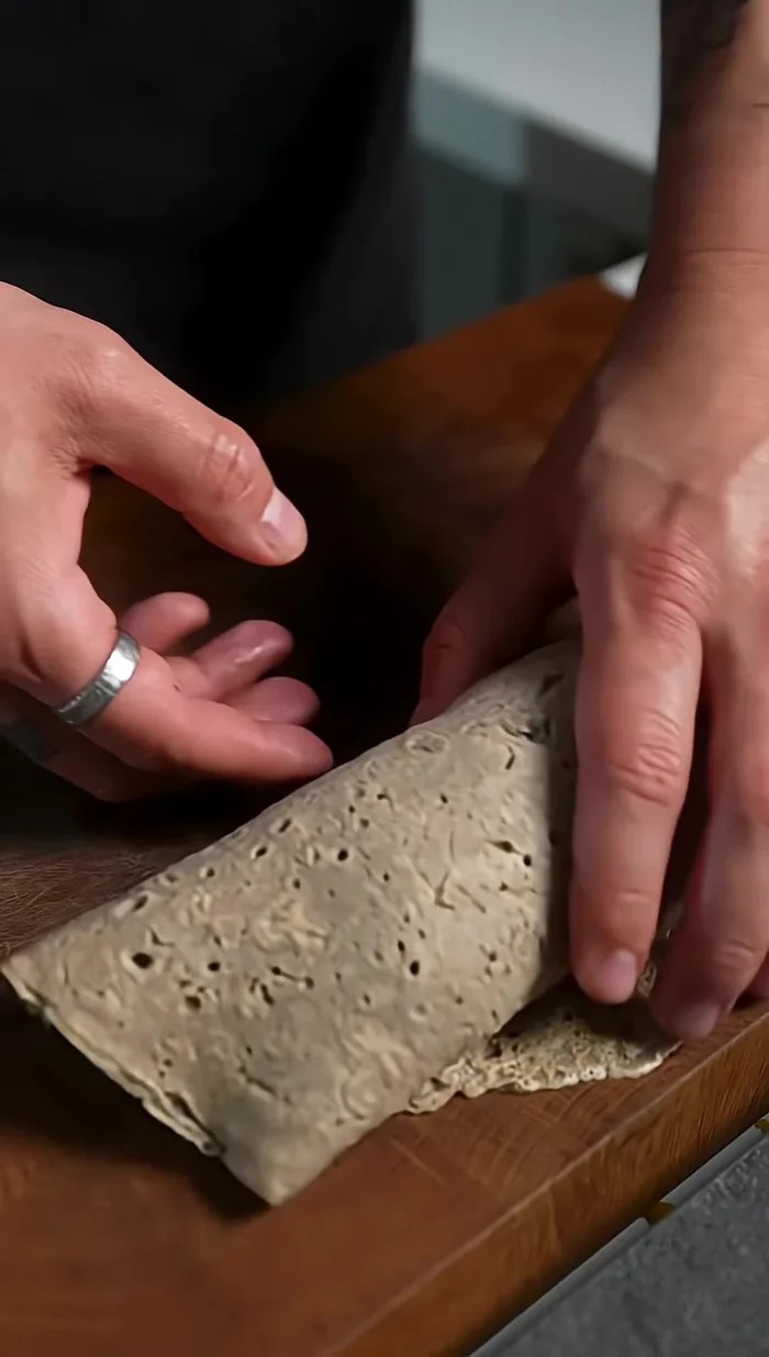 Étaler la pâte à crêpe. Ajouter la farce de porc, les saucisses et les œufs durs coupés.