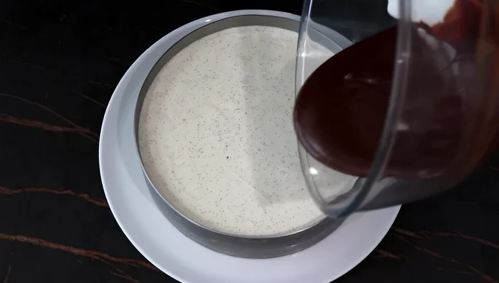 Étaler la ganache sur la crème mascarpone. Déposer des lignes de mélange chocolat blanc-pistache sur la ganache et faire des lignes perpendiculaires avec un cure-dent.