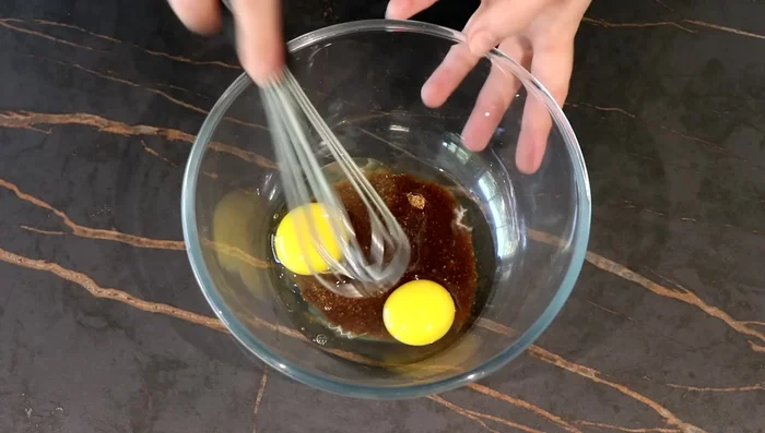 Préparer le biscuit : Mélanger le sucre de coco, les œufs, l'huile de noisette et le lait entier. Incorporer la farine, le cacao, la levure et la poudre d'amande. Verser dans un moule beurré et chemisé.