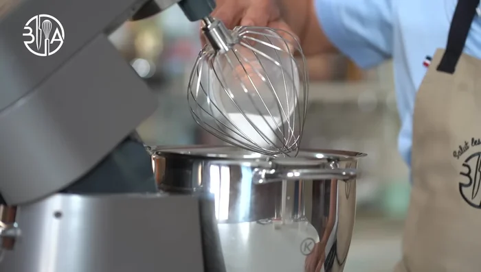 Réaliser la base du gâteau à la pistache: battre les blancs d'œufs en meringue. Mélanger la poudre d'amandes, la poudre de pistaches et le sucre.