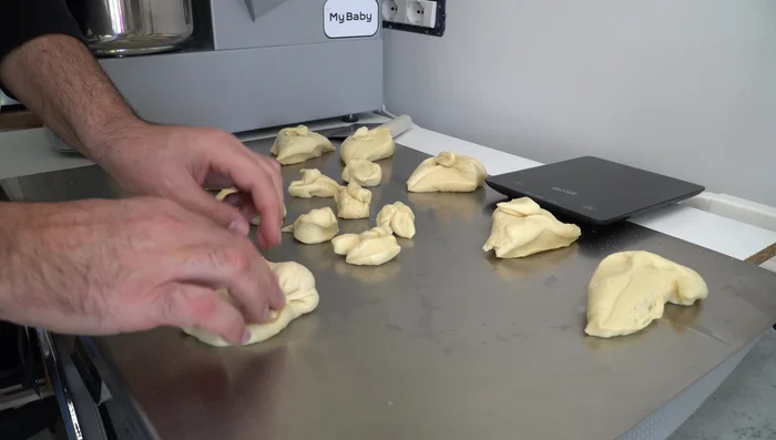 Former des boules avec les morceaux de pâte à brioche, et donner une forme de goutte à la pâte réservée pour le tuppo (389.08).